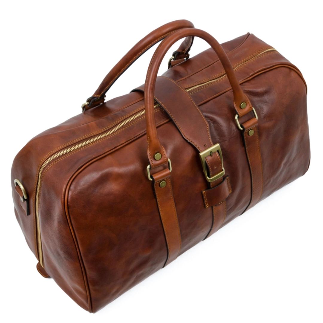 Brown leather duffel bag with gold zippers and buckles on a white background